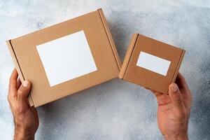 Parcel cardboard box in a man hands on a gray table background photo