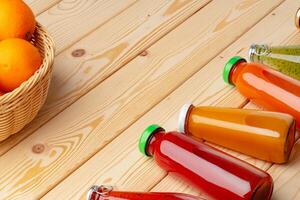Different bottles of juice on wooden table photo