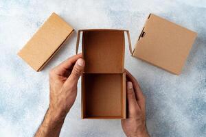 Parcel cardboard box in a man hands on a gray table background photo