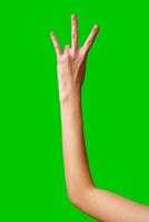 Human Hand Displaying the Number Three Against a Solid Green Background photo