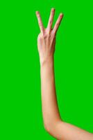 Human Hand Displaying the Number Three Against a Solid Green Background photo