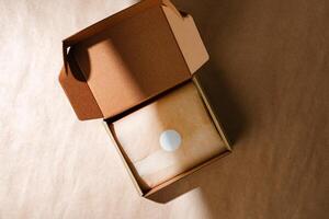 A sealed kraft box containing a wrapped item, positioned on a textured brown surface for an unboxing experience photo