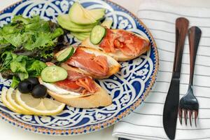 Freshly made open-faced sandwiches topped with smoked salmon and cucumber, served with a side salad photo