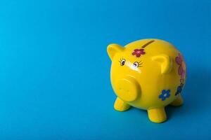 Yellow piggy bank on blue background photo