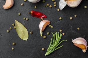 Garlic cloves and spices on black background photo