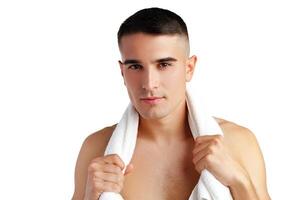 Young smiling man with towel on shoulders posing at camera on white background photo