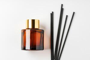 A minimalist display of essential oil and black diffuser sticks on a clean white background photo