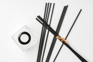 A minimalist display of essential oil and black diffuser sticks on a clean white background photo
