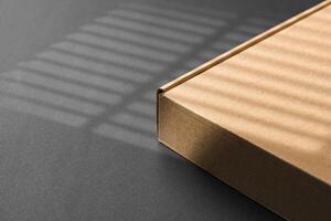 A cardboard box casting shadows on a dark surface in a striped light pattern photo