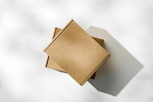 Three brown cardboard boxes arranged on a light surface with soft shadows photo