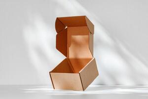 An open cardboard box rests on a bright white surface with soft shadows highlighting its edges and structure in natural light photo