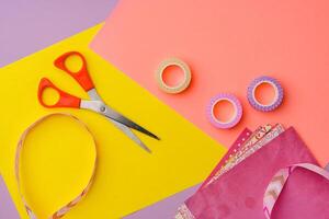 Scissors and decorative tape on colorful craft paper in a bright workspace photo