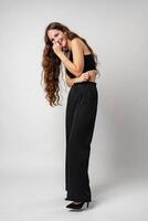 Smiling Young Woman Posing in a Black Top Against a Grey Background photo