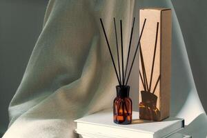 Liquid home perfume in glass diffuser with sticks on chair photo