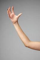 Outstretched Bare Arm With a Relaxed Hand Against a Gray Background photo