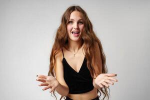 Joyful Young Woman Gesturing With Hands on a Plain Background photo