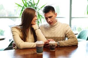 Smiling Couple Enjoying Warm Beverages at a Cozy Cafe on a Sunny Afternoon photo