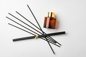 A minimalist display of essential oil and black diffuser sticks on a clean white background photo