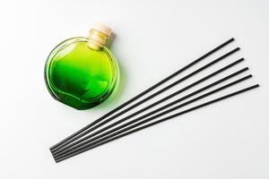 A minimalist display of essential oil and black diffuser sticks on a clean white background photo