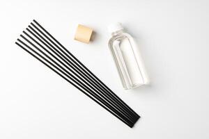 A minimalist display of essential oil and black diffuser sticks on a clean white background photo
