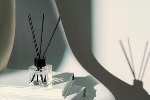 Liquid home perfume in glass diffuser with sticks on chair photo