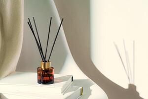 Liquid home perfume in glass diffuser with sticks on chair photo