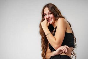 Smiling Young Woman Posing in a Black Top Against a Grey Background photo
