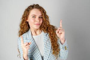 Young Woman With Curly Hair Pointing Upwards in a Studio Setting photo