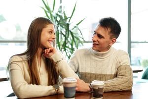 Smiling Couple Enjoying Warm Beverages at a Cozy Cafe on a Sunny Afternoon photo