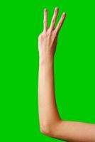 Human Hand Displaying the Number Three Against a Solid Green Background photo
