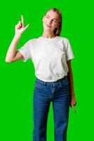 Young Woman Pointing Up Against Green Background photo