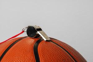 Close-Up View of a Whistle Resting on a Basketball Against a Grey Background photo