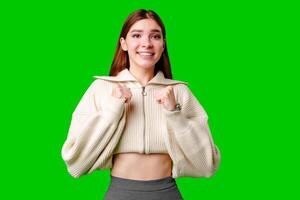 A woman wearing a white sweater and a gray skirt stands in a casual pose, looking at the camera. photo