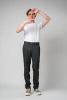 Young Man Making Frame With Hands Focusing On an Imaginary Object Against a Plain Background photo