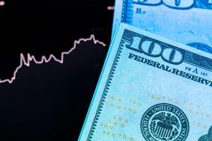 Dollars in front of a monitor with a price chart. Forex and trading. photo