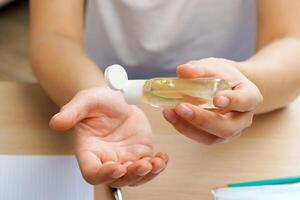 Young man applying sanitizer gel on his hands while sitting at his working table photo