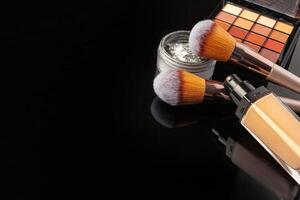 Professional makeup brushes and tools, make-up products set on dark table photo