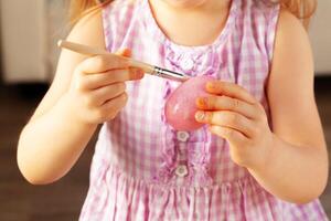 Cropped image of a little girl painting eggs for Easter photo