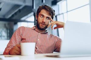 Puzzled thoughtful businessman sitting at his working table in an office photo