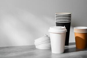 Stack of coffee cups in various colors with lids on a gray surface photo