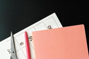 Notepad with pen and scissors on black table close up photo