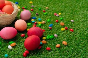 Colored eggs and vibrant candies on grass. Easter composition photo