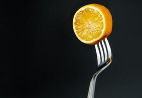 lemon on the fork on black background photo