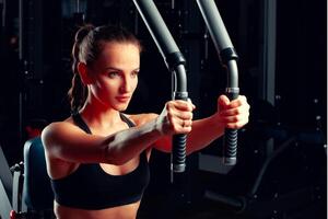 Young attractive woman doing exercises for arms in a training machine photo