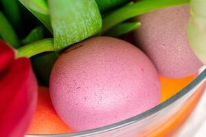 Vibrant Easter eggs with flowers in a glass jar close up, cropped image photo