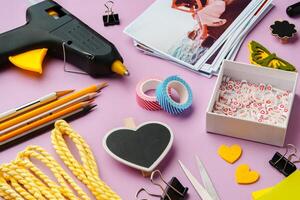 Crafting supplies arranged on a pink background, including glue gun, scissors, and decorative items for DIY projects photo