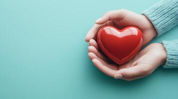 Hands holding a shiny red heart symbol against a soft blue background to convey love and affection in a warm, inviting atmosphere photo