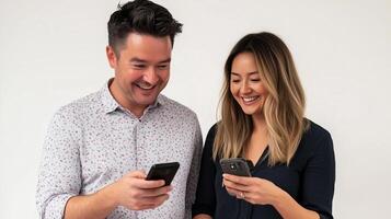 Two people smiling and interacting with smartphones in a casually styled indoor setting during the daytime photo