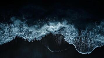 Waves crashing against a dark shoreline create a dramatic contrast during twilight by the ocean photo