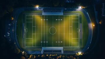 Aerial view of a well-lit soccer field at night surrounded by trees and a parking lot photo